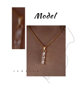 Detail showing a gold necklace with three vertical rectangular clear zircon stones on a model