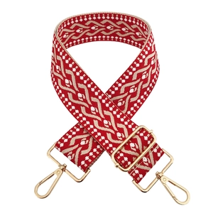 Close-up of red and beige jacquard woven strap with golden metal hooks and buckle