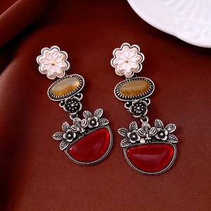 Detailed close-up of vintage floral oval drop earrings with red stones on brown silk background