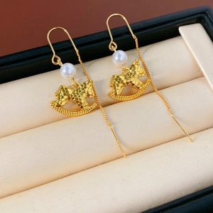 Detailed macro view of golden rocking horse earrings with pearls in a luxury jewelry box
