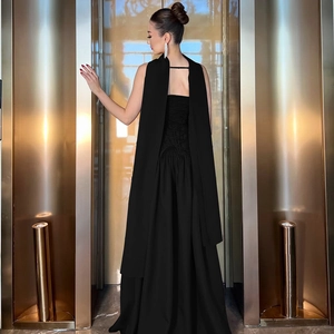 Detail of elegant black evening dress featuring back lace-up design and a long flowing cape
