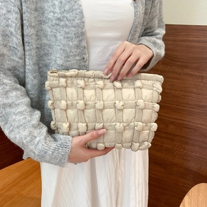 Detail view of beige quilted bubble checkered vanity bag with premium metal zipper closure
