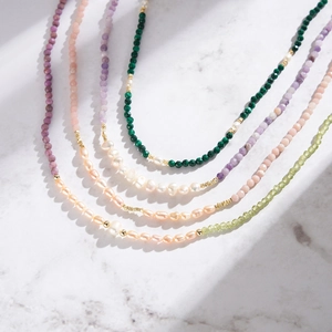 Elegant freshwater pearl and natural stone beaded necklaces on white marble surface