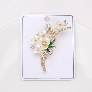 Macro de l'élégante broche fleur de prunier en émail blanc avec métal doré et feuilles