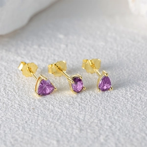 Macro shot of purple heart, oval, and teardrop crystal earrings in gold plating