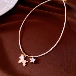 Detailed macro view of gold unicorn and star charms on an elegant white pearl necklace