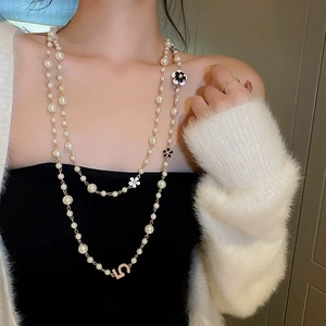 Elegant layered pearl necklace with gold chain and floral pendants worn by a model