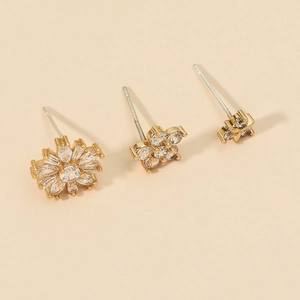 Detailed view of gold earrings set with sun flower and clover shapes inlaid with zircons