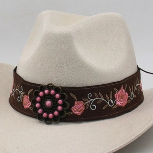 Close-up of beige felt cowboy hat with brown floral embroidery strap and metal buckle