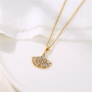 Golden ginkgo leaf necklace with zircon inlay displayed on a white ceramic plate