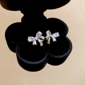 Detailed macro view of silver bow stud earrings with sparkling cubic zirconia in a box