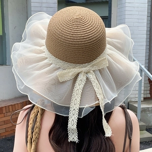 Detail of elegant summer straw hat with oversized white organza brim and lace ribbon bow