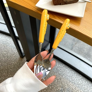 Close-up of yellow dinosaur ceramic handle stainless steel spoon and fork set