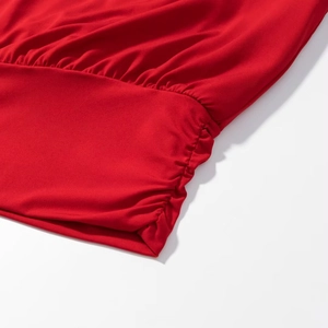 Détail du tissu froncé rouge montrant la texture plissée et la bretelle de l'épaule