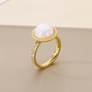 Macro shot of gold-plated ring with central pearl and sparkling cubic zirconia stones