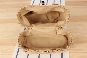 Detail view of woven straw bag interior with khaki fabric lining and gold metal clasp
