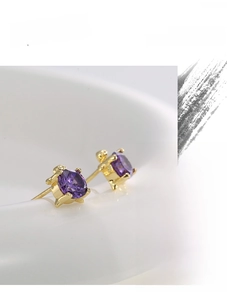 Detailed macro view of turtle stud earrings with purple zircons and gold plating