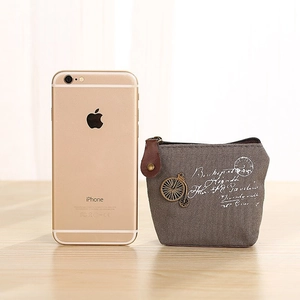 Vintage grey canvas coin purse with bronze bicycle charm on a wooden background