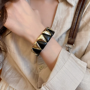 Detail of wide geometric elastic bracelet with gold mirror and black matte finish on wrist