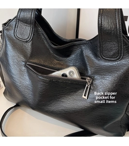 Detail view of the back zipper pocket on a black leather tote bag for secure small items