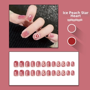Close-up of translucent peach pink press-on nails with red hearts and star patterns