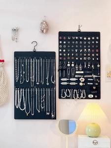 Dual wall-mounted black felt jewelry organizers for necklaces and earrings in home setting