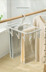 Close-up of a white plastic multi-clip drying rack with a towel bar for socks and laundry