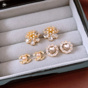 Macro detail of 14k gold plated pearl floral earrings with luxury brand logo style