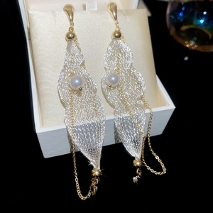 Macro detail of drop earrings with mesh leaves, pearls and tassels in a jewelry box