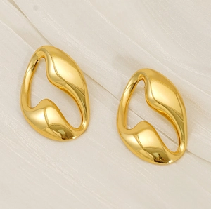 Detailed view of irregular fluid gold earrings on soft textured fabric background