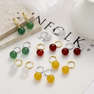 Detail of round hoop earrings with colorful spherical charms in green, red, and white