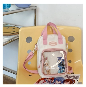 Detail of white and pink canvas ita bag showing transparent PVC window on a yellow chair