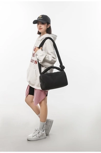 Detail of black quilted puffer shoulder bag featuring a padded knotted strap and soft finish