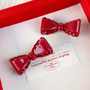 Set of two vintage red bow hair clips with hollow lace design on textured card