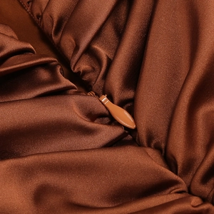Detailed view of the invisible zipper on a smooth caramel satin party dress fabric