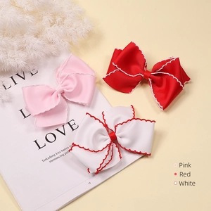 Detailed view of pink, red, and white grosgrain ribbon bow clips with scalloped edges