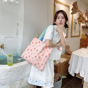 Detail of pink quilted canvas shoulder bag with cartoon bear and bow patterns