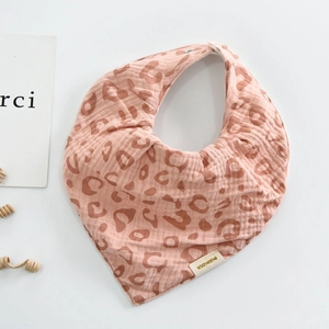 Detail of pink leopard print cotton muslin baby bib with snap closure on white background