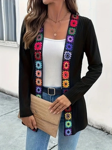 Detail of black ribbed cardigan featuring vibrant colorful crochet floral embroidery trim