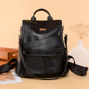 Detail of black leather patchwork backpack featuring golden metal buckle and texture