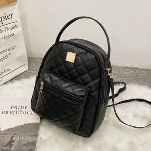 Elegant black quilted mini backpack made of PU leather with golden hardware on white fur