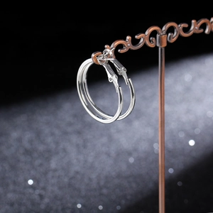 Macro shot of silver large hoop earrings with polished finish on a vintage stand