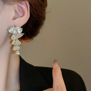 Close-up of model wearing tiered silver tassel earrings with a layered shell design