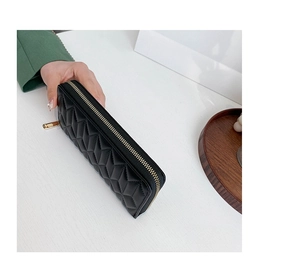 Detail of hand holding a black quilted PU leather long wallet with gold zipper closure