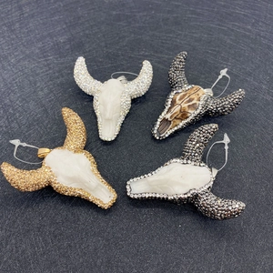 Detailed view of four bull head pendants with rhinestones in gold, silver, and brown tones