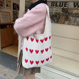 Detail of white knitted tote bag with red hearts and cable knit texture pattern