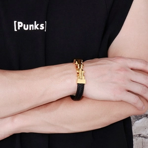 Primo piano di un bracciale in pelle intrecciata nera con chiusura in metallo dorato