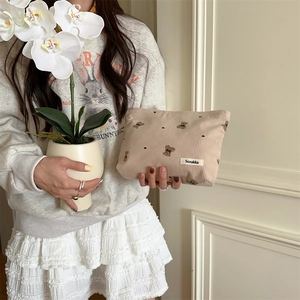 Close-up of beige corduroy pouch with cute bear and heart pattern held by a hand