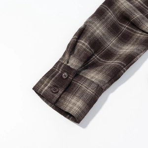 Détail du poignet boutonné sur une chemise en flanelle à carreaux marron chiné