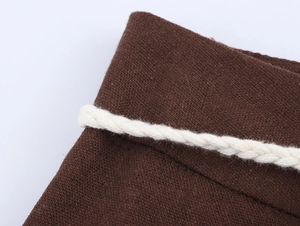 Detail of white braided rope belt on brown linen texture ethnic style straight trousers